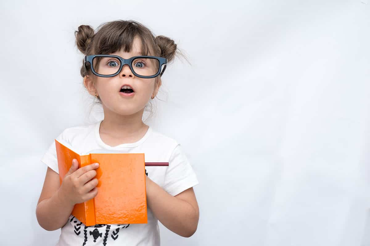 little girl writing in orange book