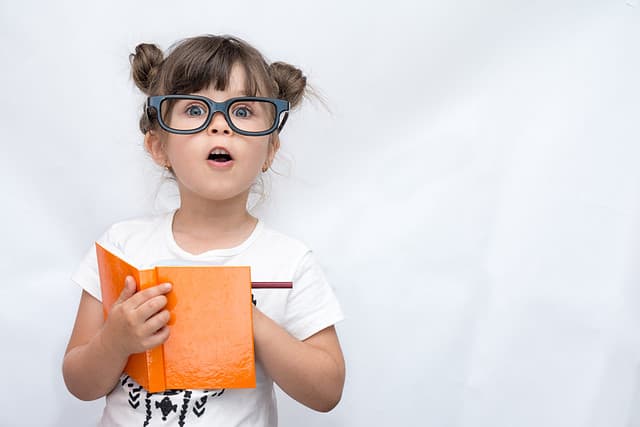 little girl writing in orange book