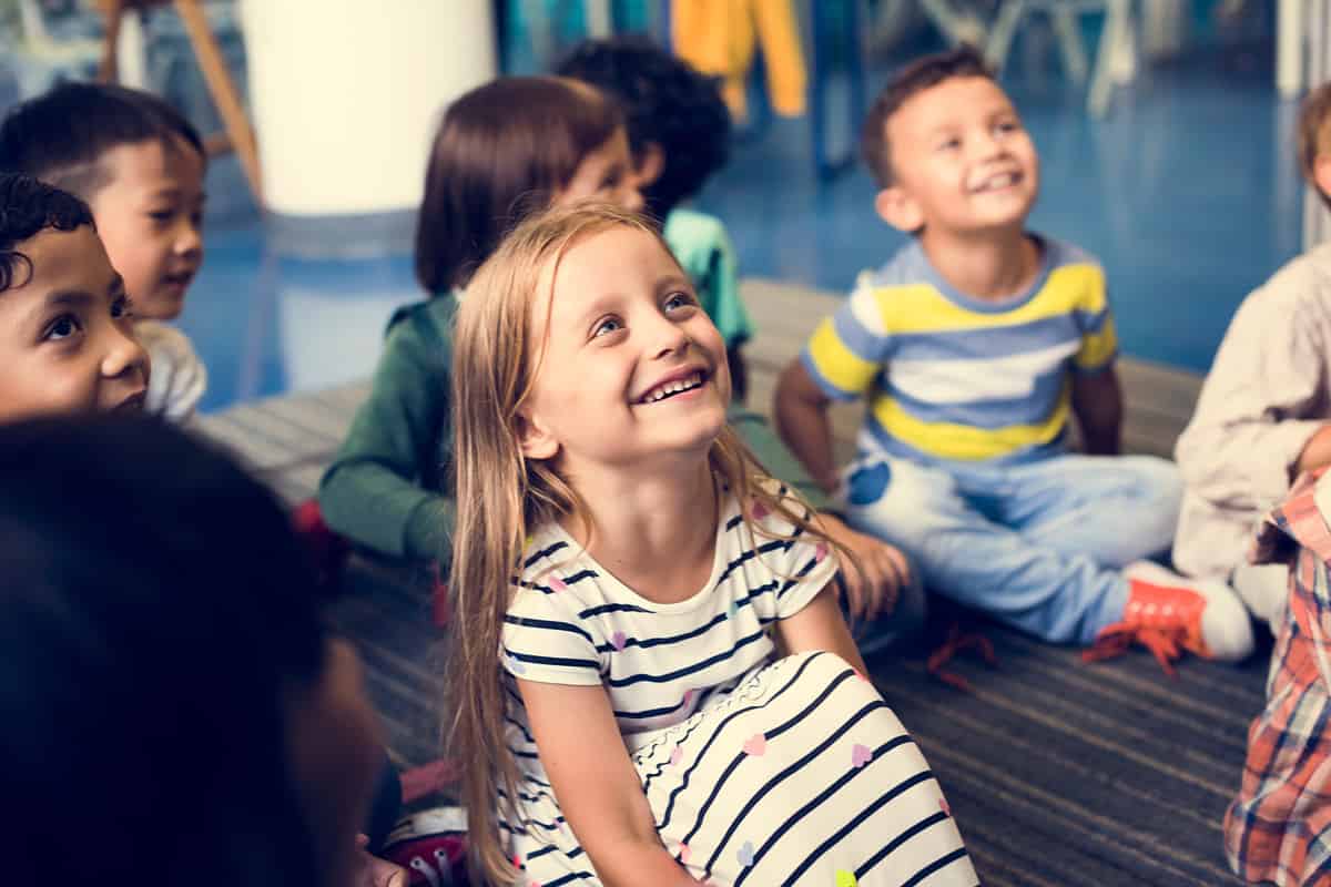 Photo of a happy elementary grade girl seated on the floor in class.