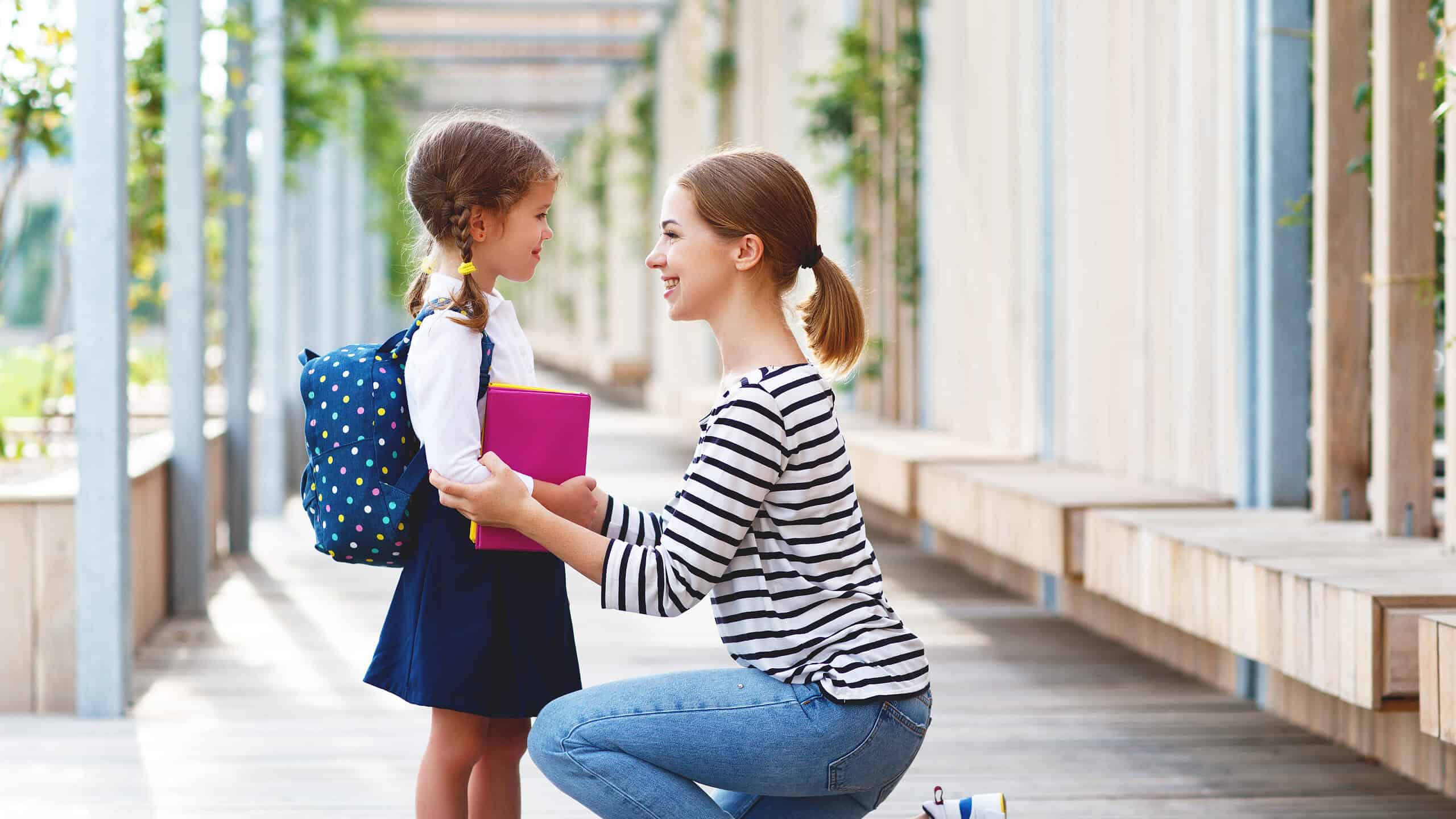 first day at school. mother leads a little child school girl in first grade