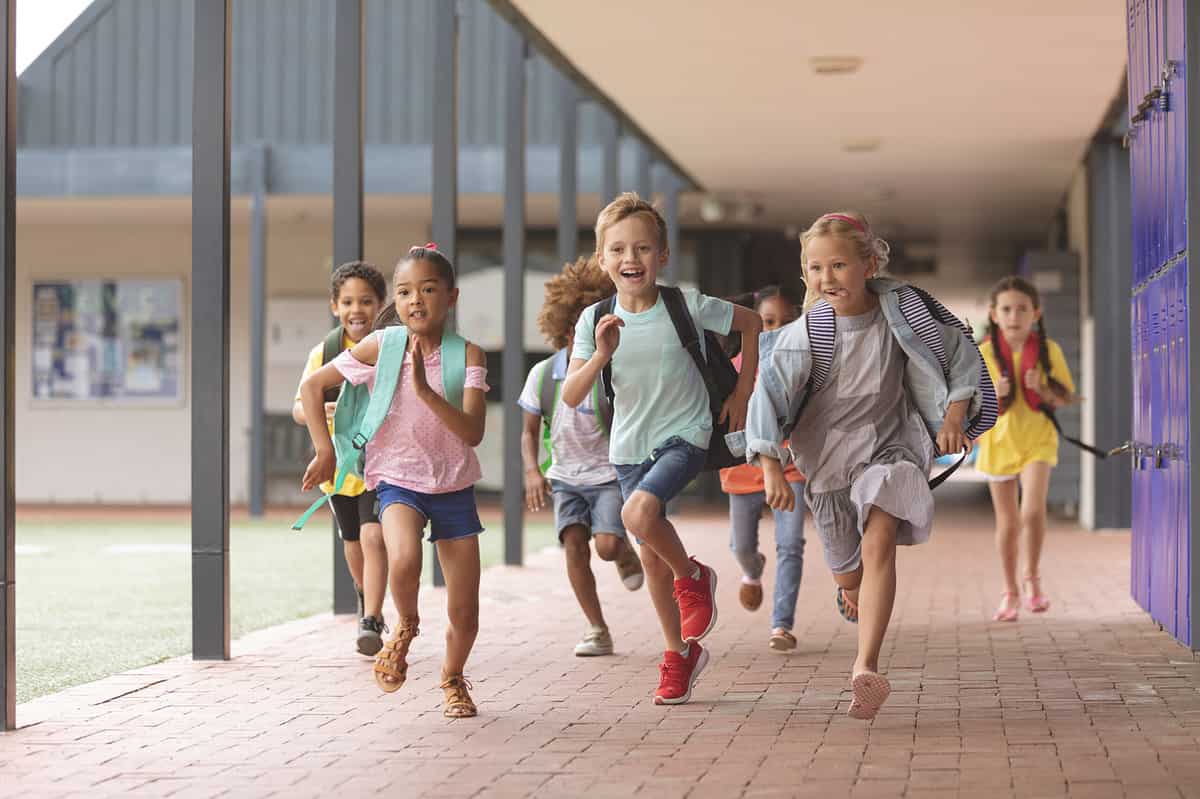 Front View Of Happy Diverse School Kids Running In Corridor