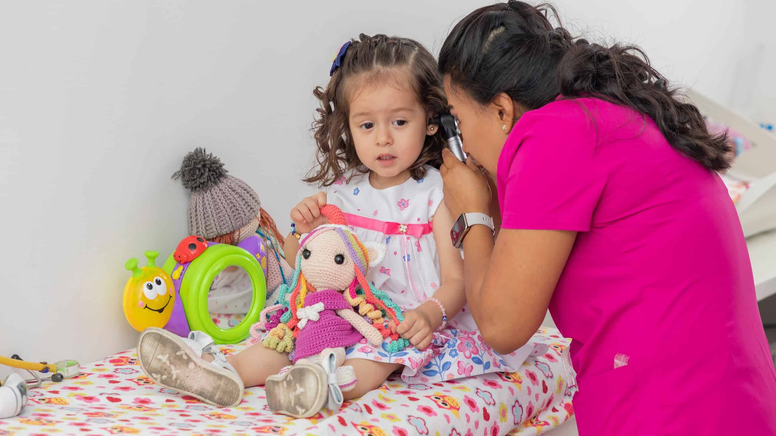 Female doctor examining little girl's ear