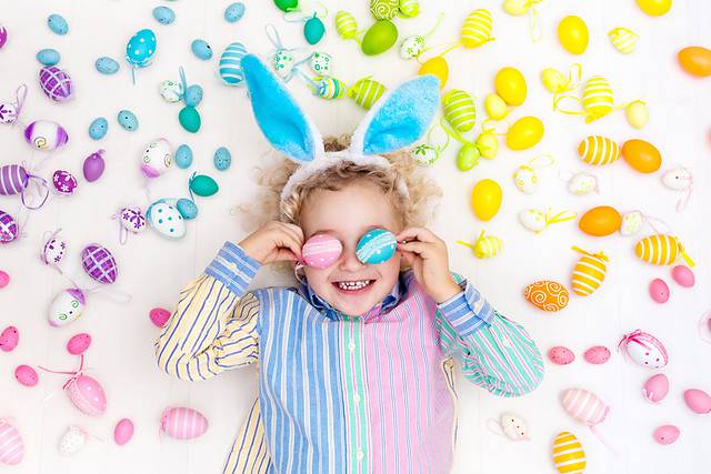 Little kid with Easter eggs around them and on their eyes