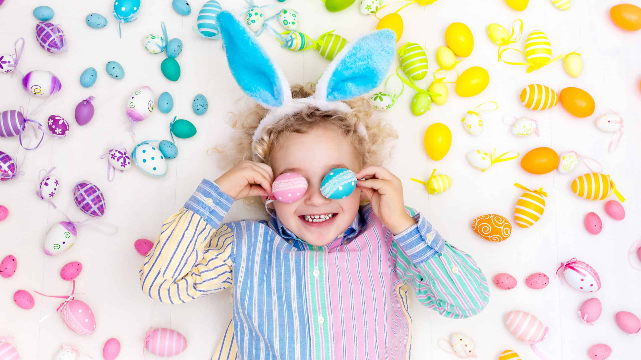 Little kid with Easter eggs around them and on their eyes