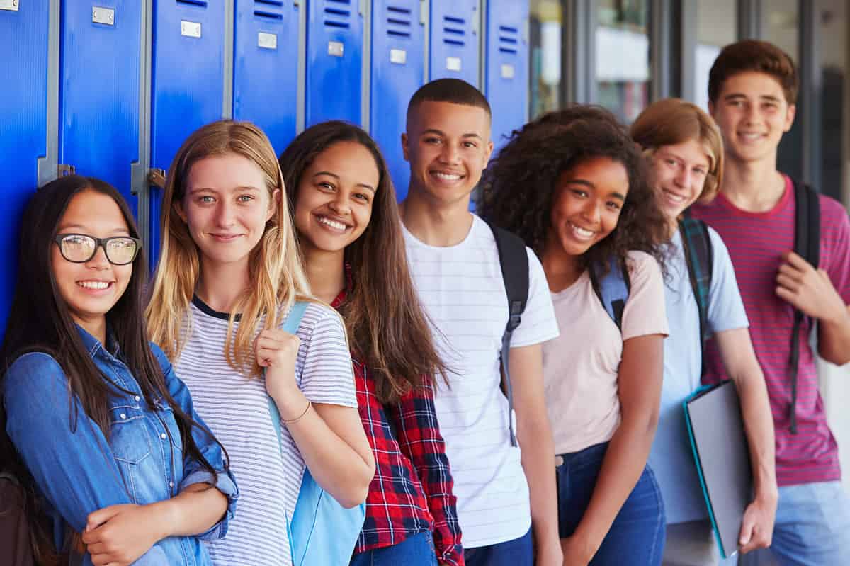 Teenage school kids smiling to the camera in the school corridor