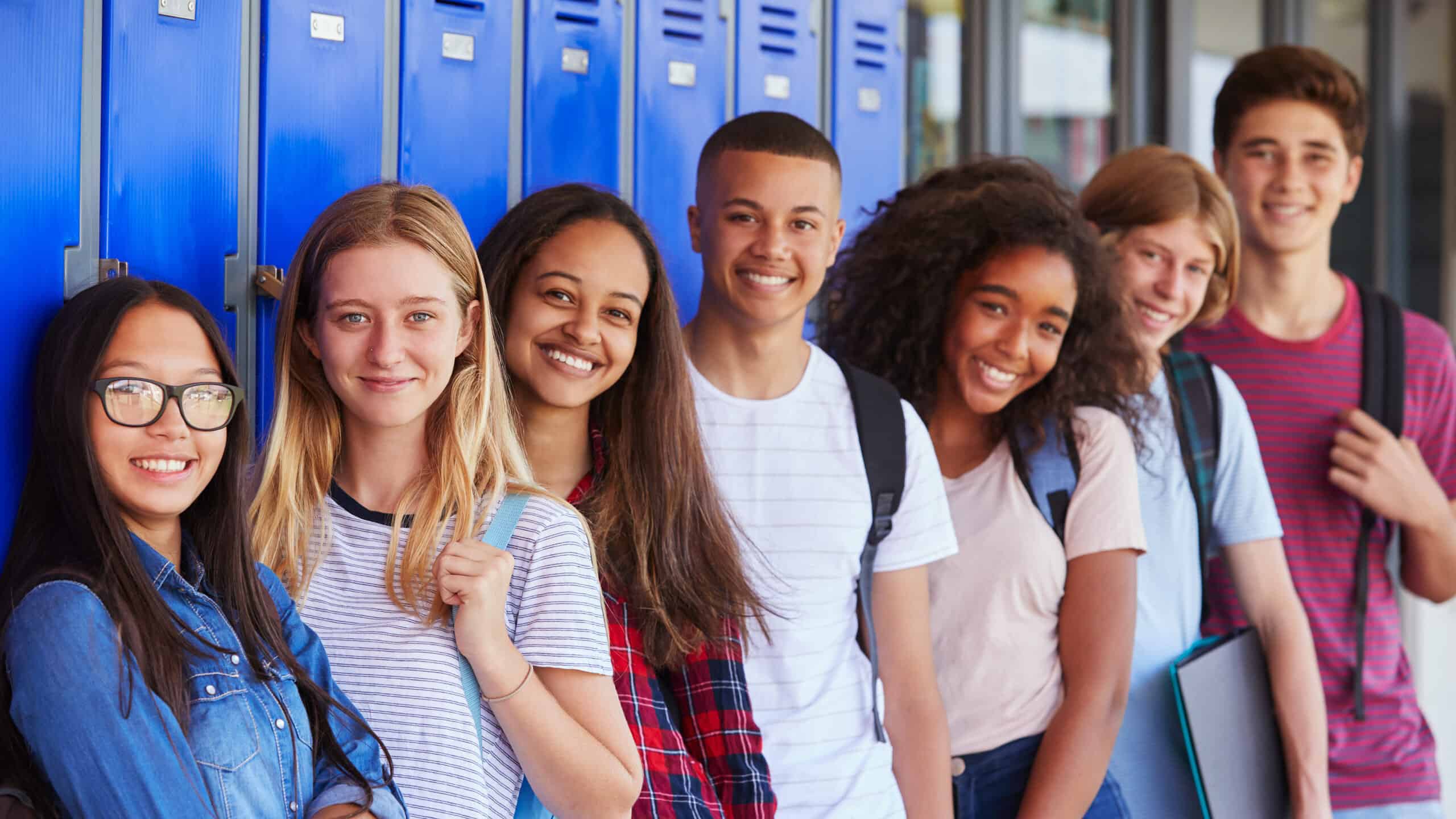 Teenage school kids smiling to the camera in the school corridor