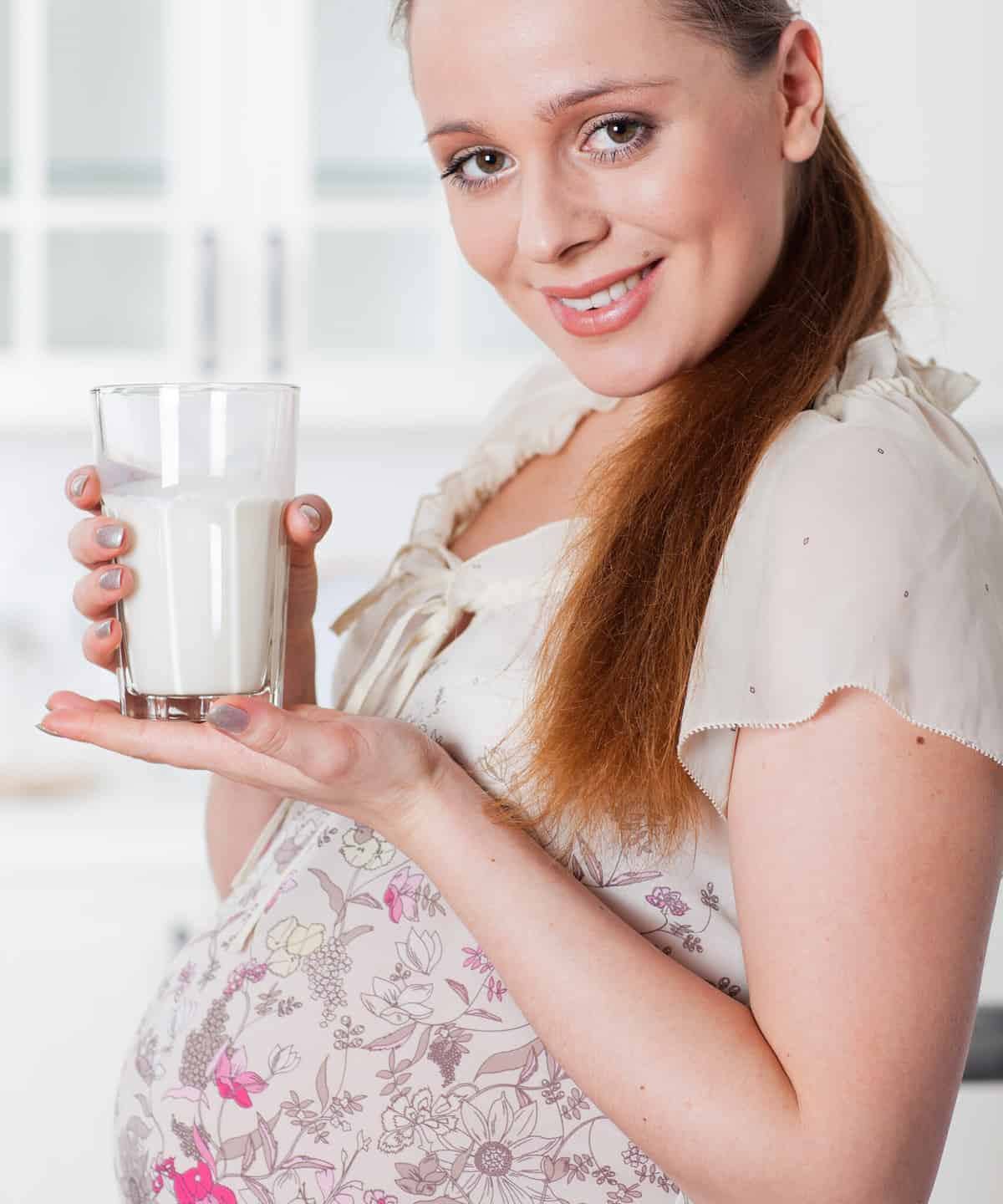 Smiling pregnant woman with a glass of milk