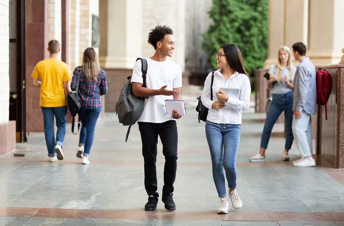 University students chatting while walking  through vibrant campus grounds.