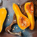 Butternut squash on wooden board over rustic background. Healthy fall cooking concept
