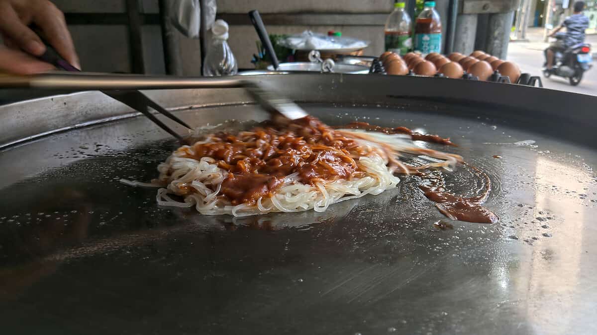 White noodle and brown sauce with metal turner on a metal pan to make a Pad Thai, Thailand