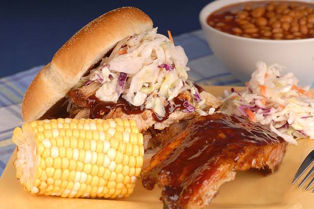 Pulled pork sandwich with slab of ribs, ear of corn, cole slaw and beans