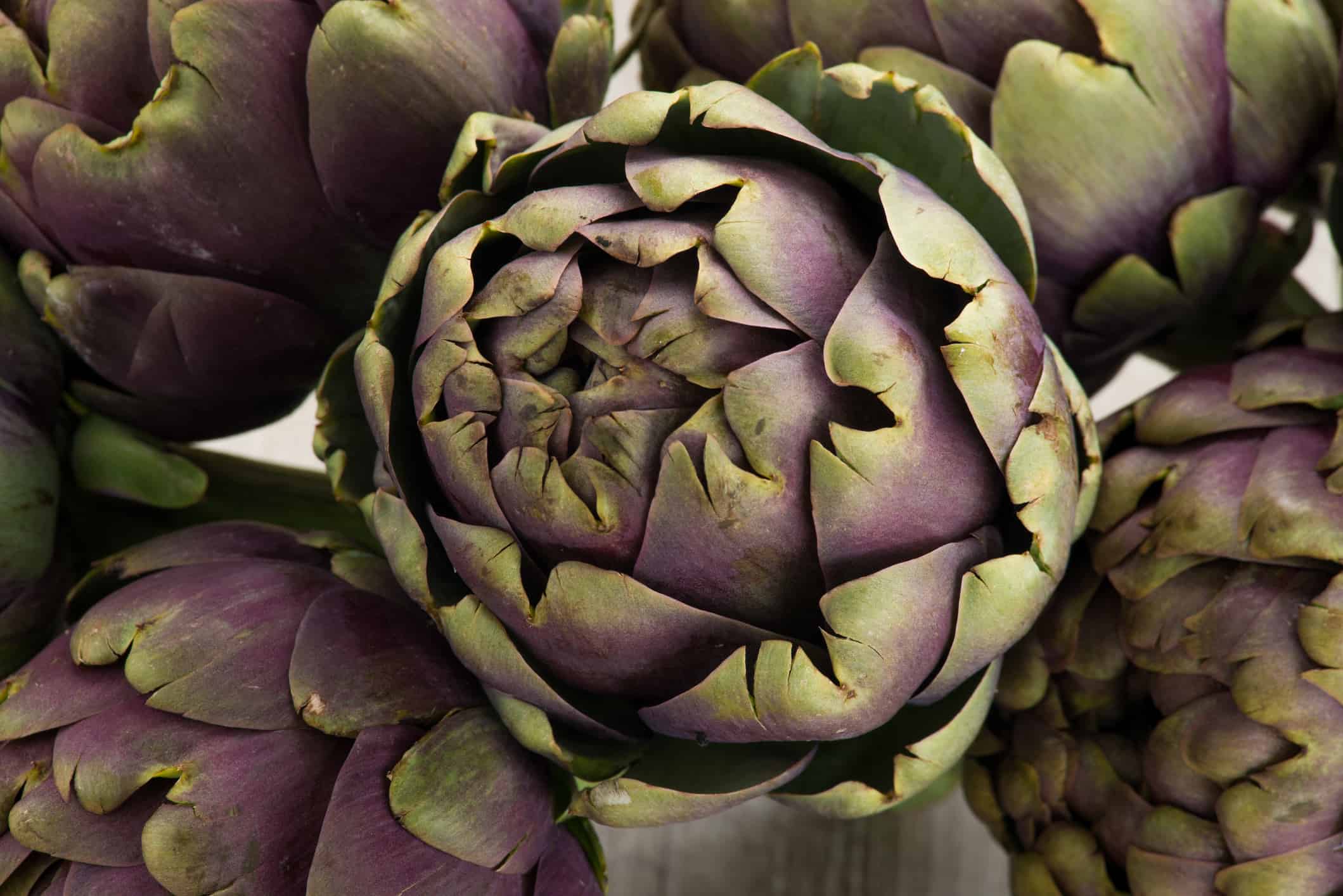 Basket with artichokes and asparagus on yellow backgroud