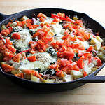 A hearty spinach nest and tomato skillet breakfast set on a wooden surface