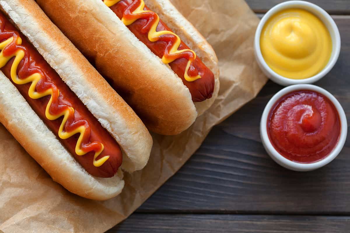 Barbecue Grilled Hot Dog with Yellow Mustard and ketchup on wooden table