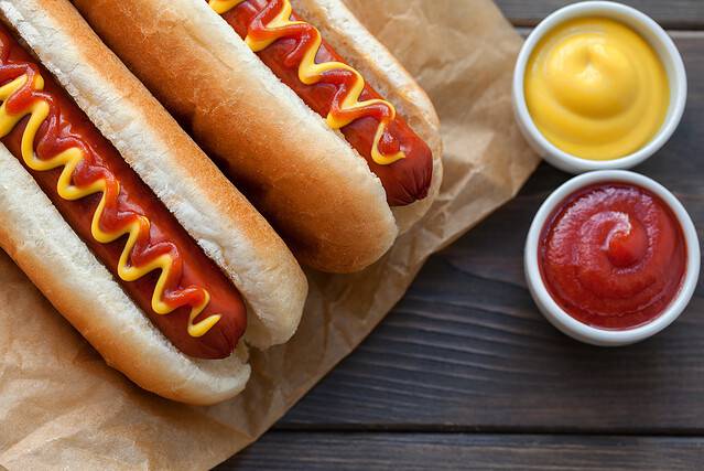 Barbecue Grilled Hot Dog with Yellow Mustard and ketchup on wooden table