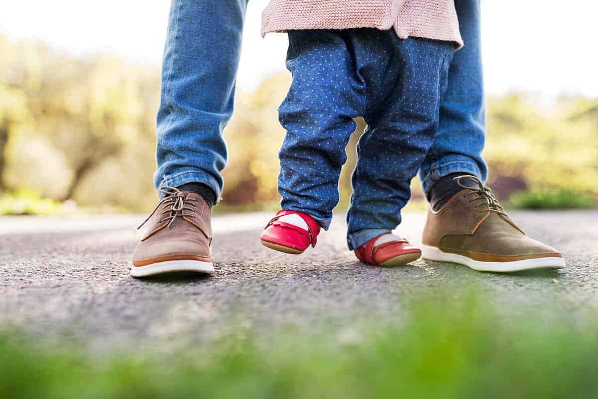 First steps of a toddler girl outside in spring nature.