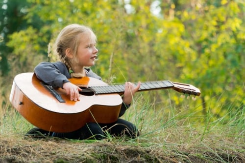 Child plays guatar. camping.Sit on the grass.Study.Music.