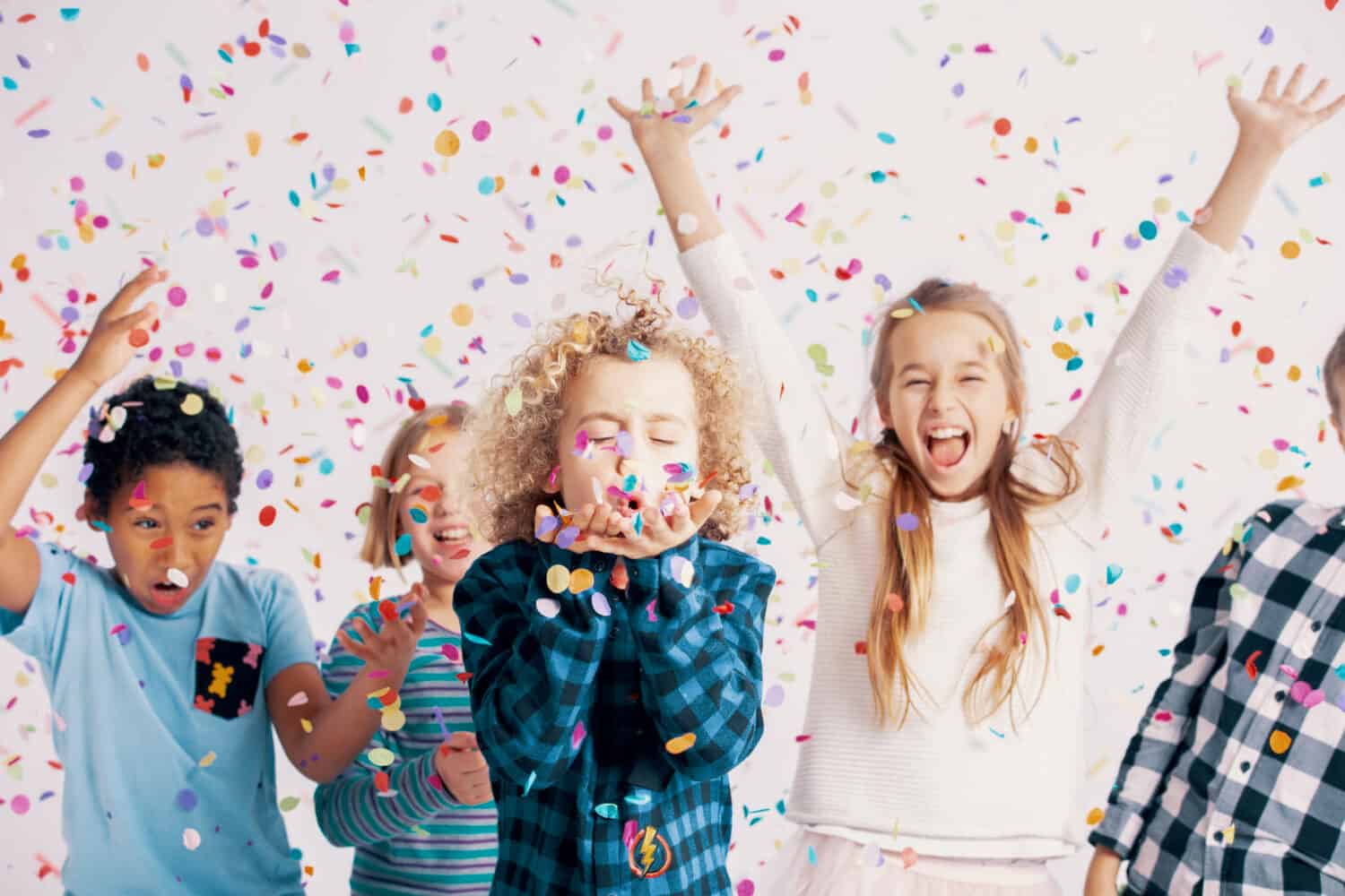 Happy multicultural group of kids having fun during birthday party with confetti