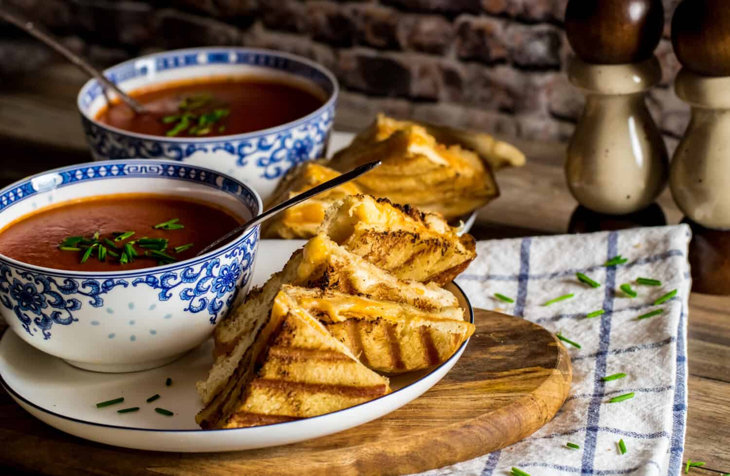 Close up of panini grilled cheese sandwiches and tomato soup against a dark background ready to eat.