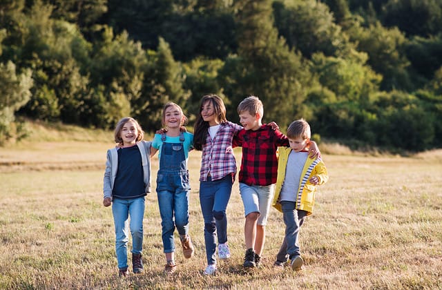 Group of school children walking on field trip in nature, arm in arm.