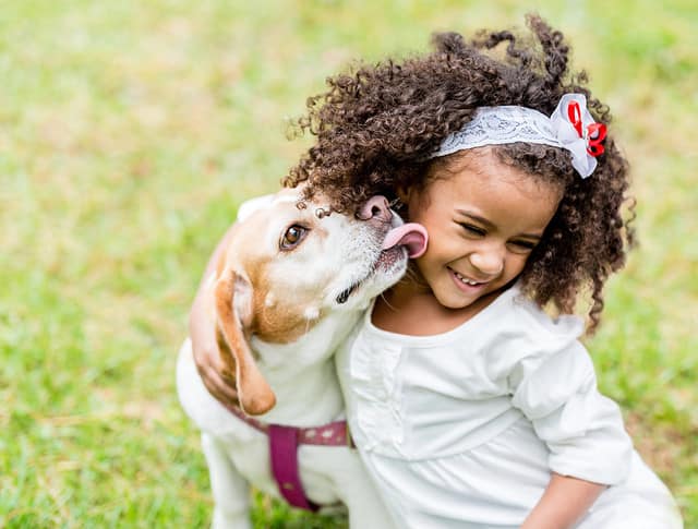 Happy girl with a dog licking her face