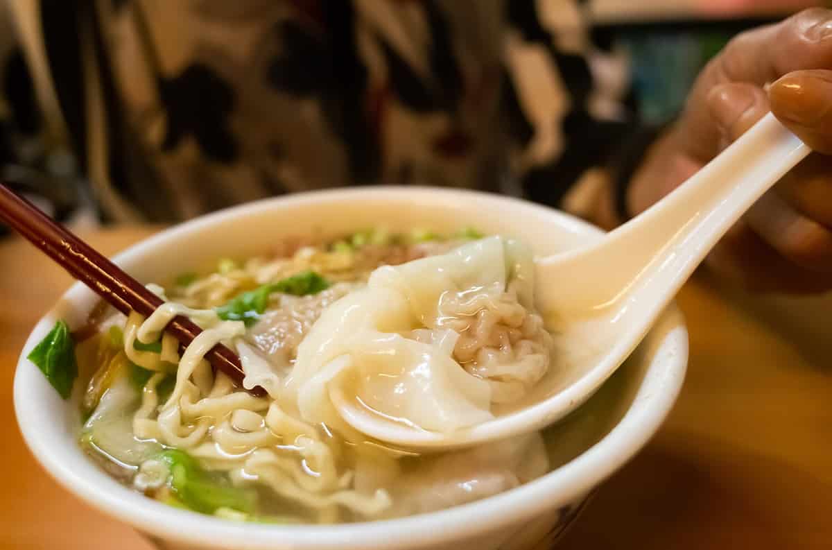 eat wonton noodles with soup on a table