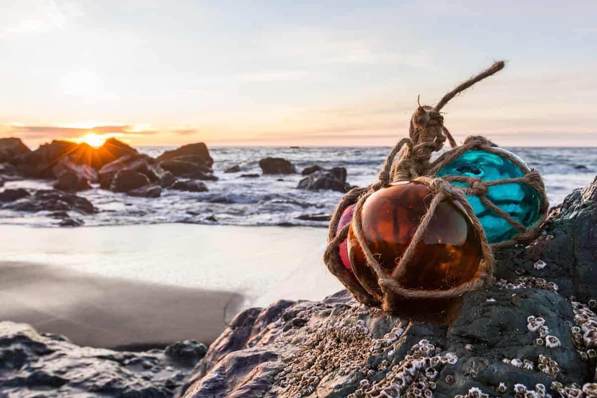 Sunset in the Oregon coast with colorful glass floats on a rock and a sandy beach and the ocean in the background