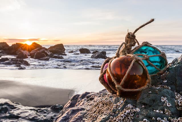 Sunset in the Oregon coast with colorful glass floats on a rock and a sandy beach and the ocean in the background