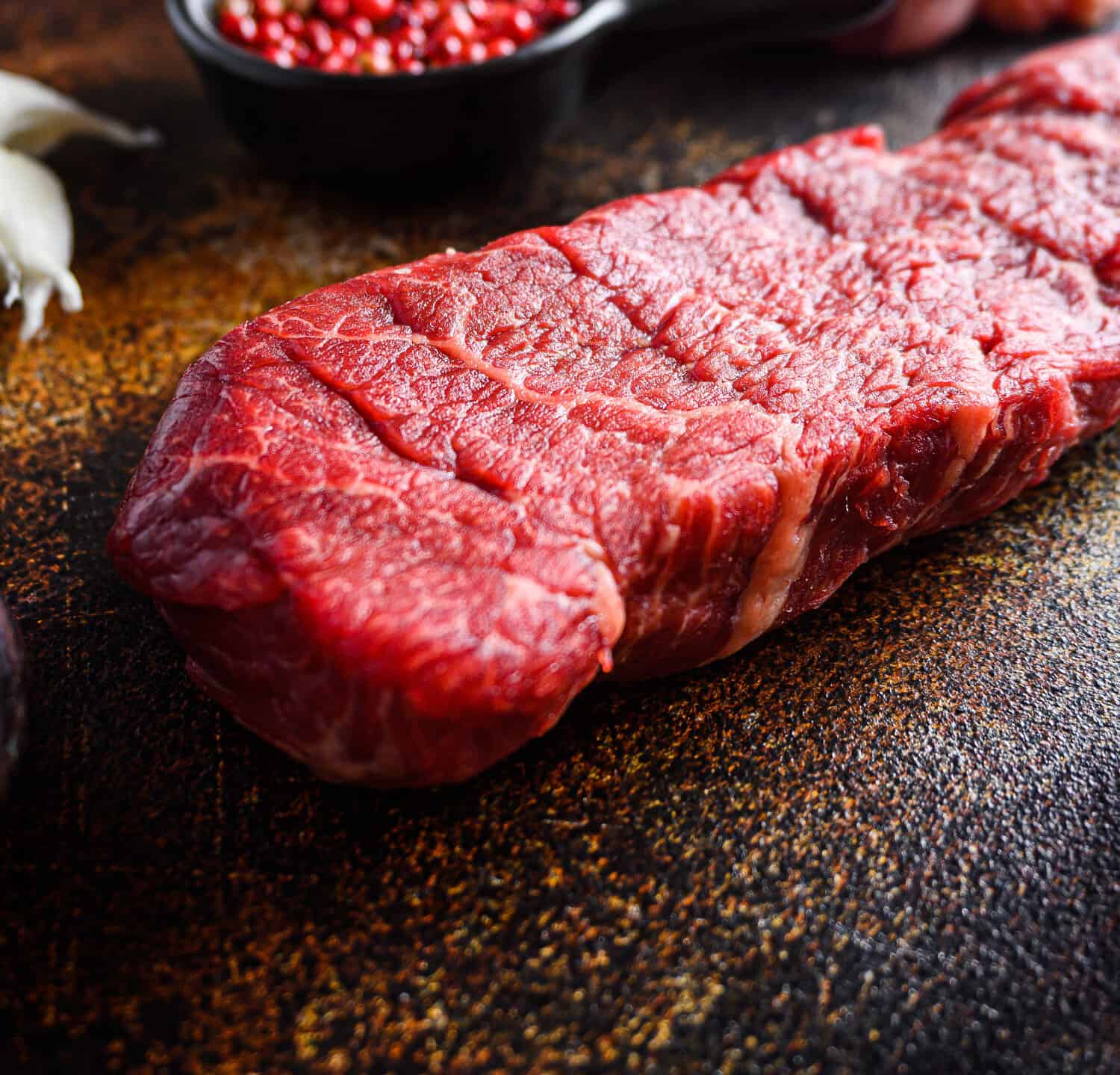 Side view Close up denver Steak, Flank steak, cut near denver alternative beef steak and a cleaver butcher meat knife a rustic metall background vertical