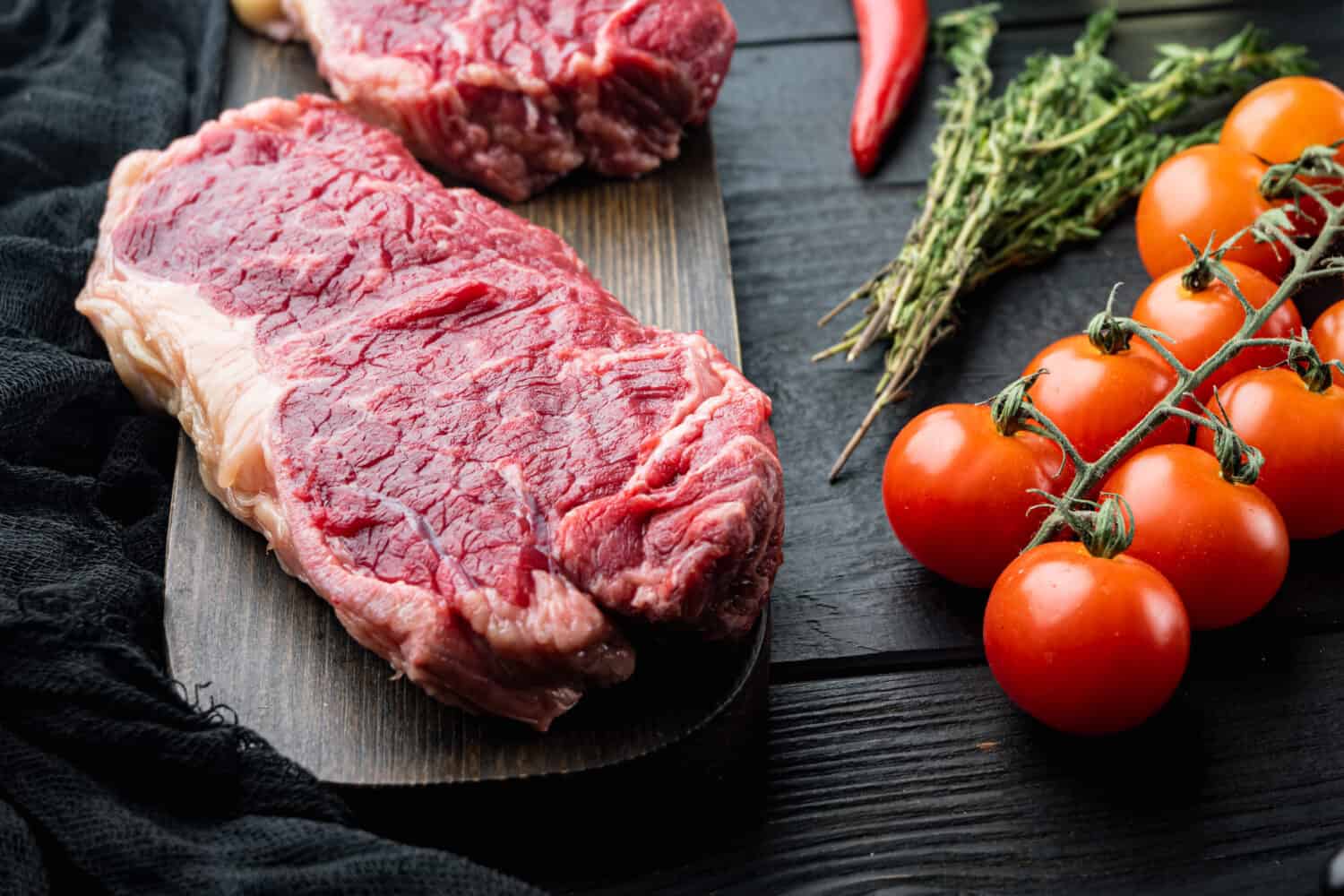 Strip steak, marbled beef meat, on black wooden table