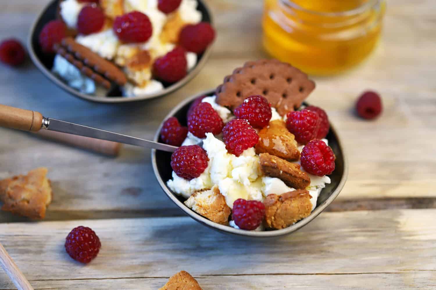 Selective focus. Delicious dessert with mascarpone cheese, raspberries and cookies.