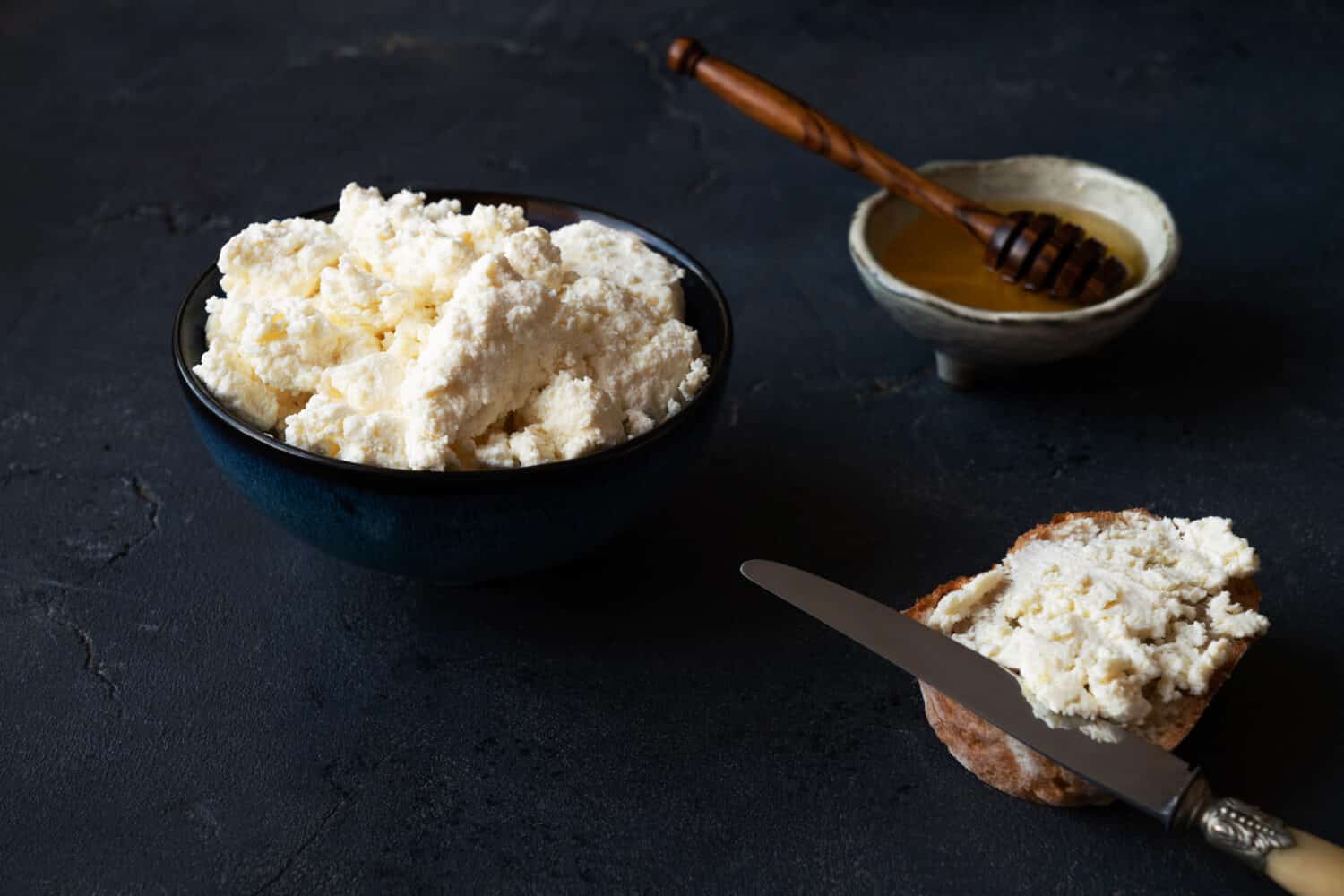 Home made fresh ricotta cheese, quark, cottage cheese, fromage frais with honey and bread. High angle.