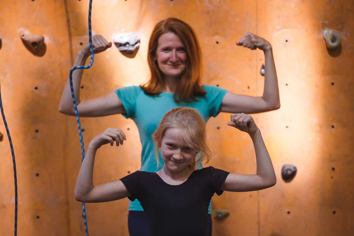 little girl rock climber and her mom posing on the bouldering wall. healthy fun active family