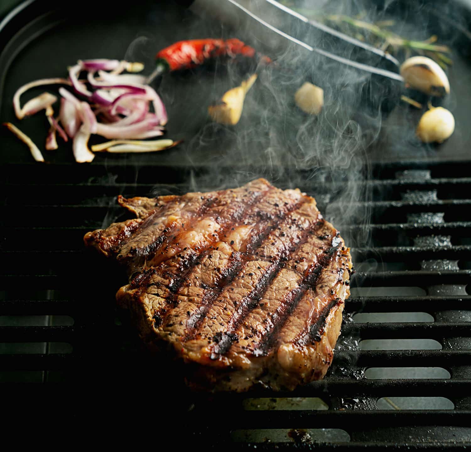 Grilling rib eye steak at home. Natural smoke. Summer grill, cooking at home concept