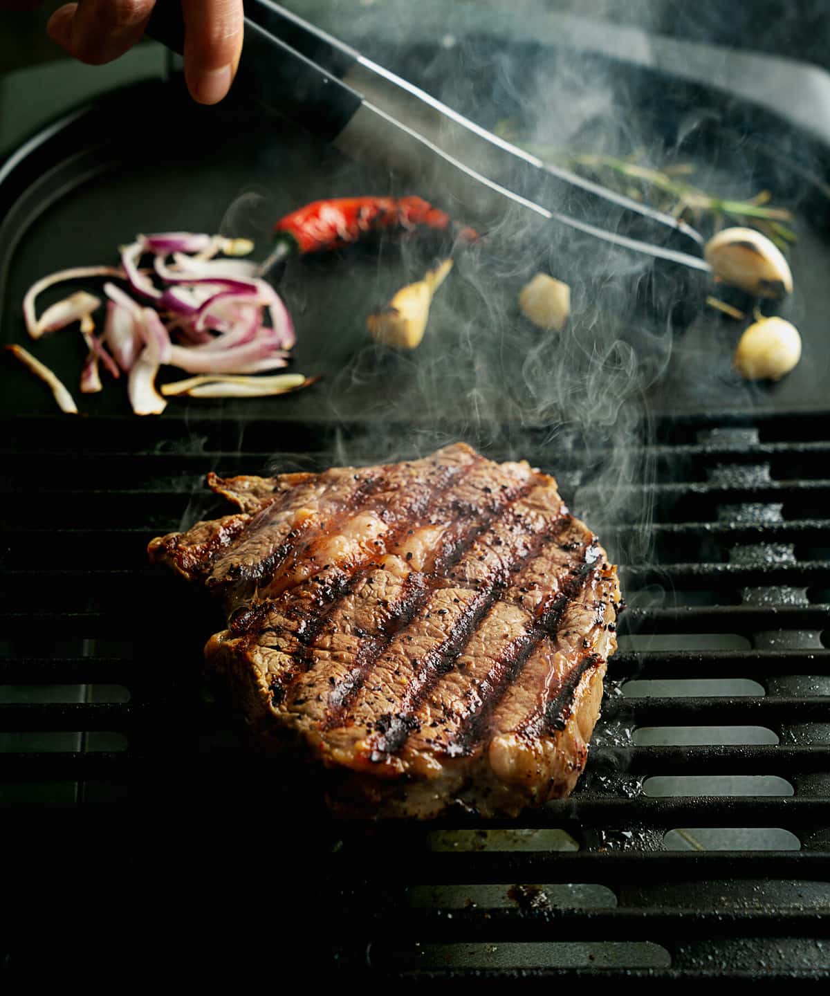 Grilling rib eye steak at home. Natural smoke. Summer grill, cooking at home concept