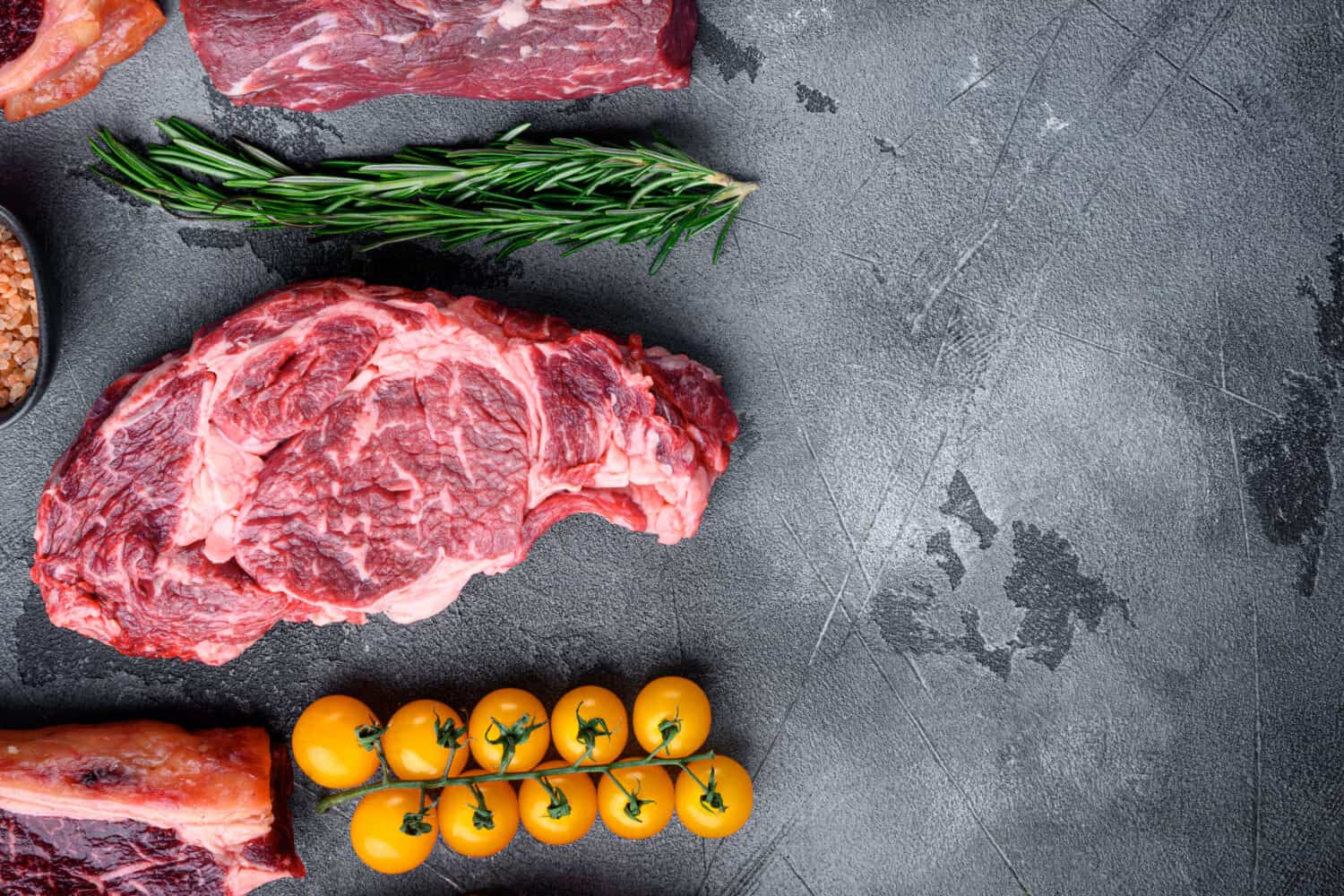 Raw meat Ribeye Steak with seasoning set, on gray stone background, top view flat lay, with copy space for text