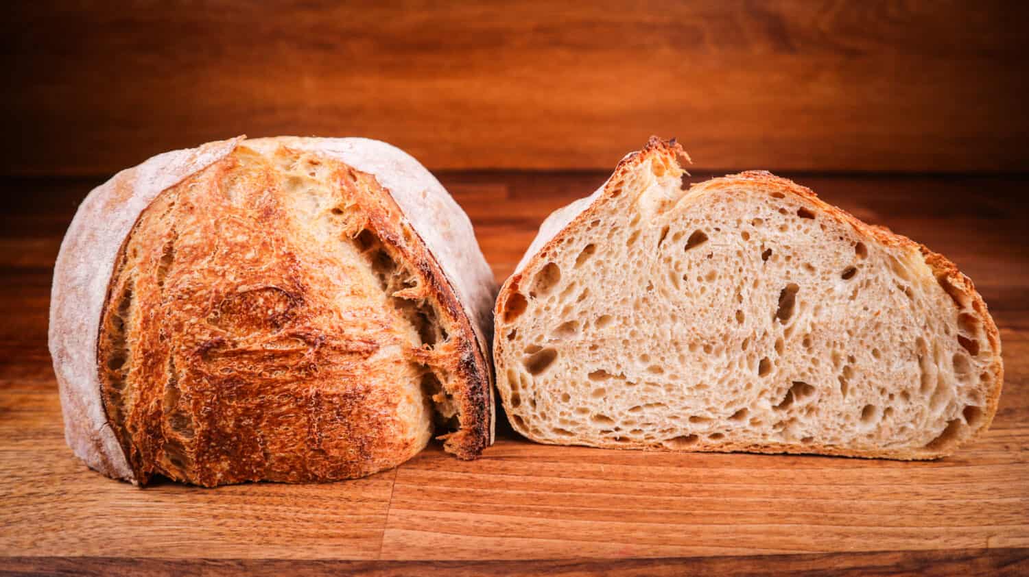 A closeup of a freshly baked, sliced sourdough bread on a wooden board