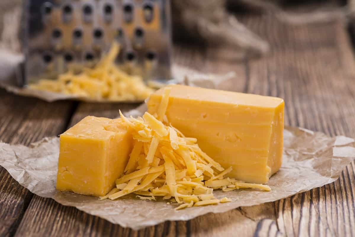 Cheddar Cheese (grated) as close-up shot on an old vintage wooden table