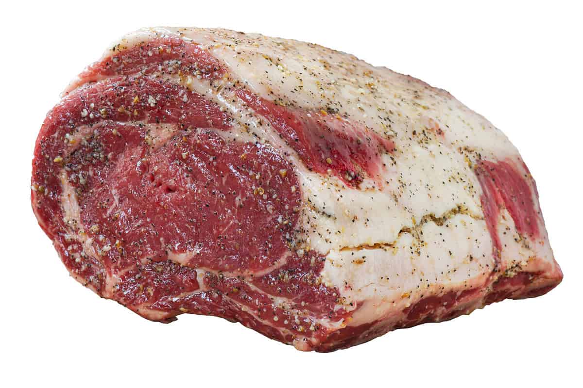 Raw prime rib roast beef with seasoning; isolated on white background