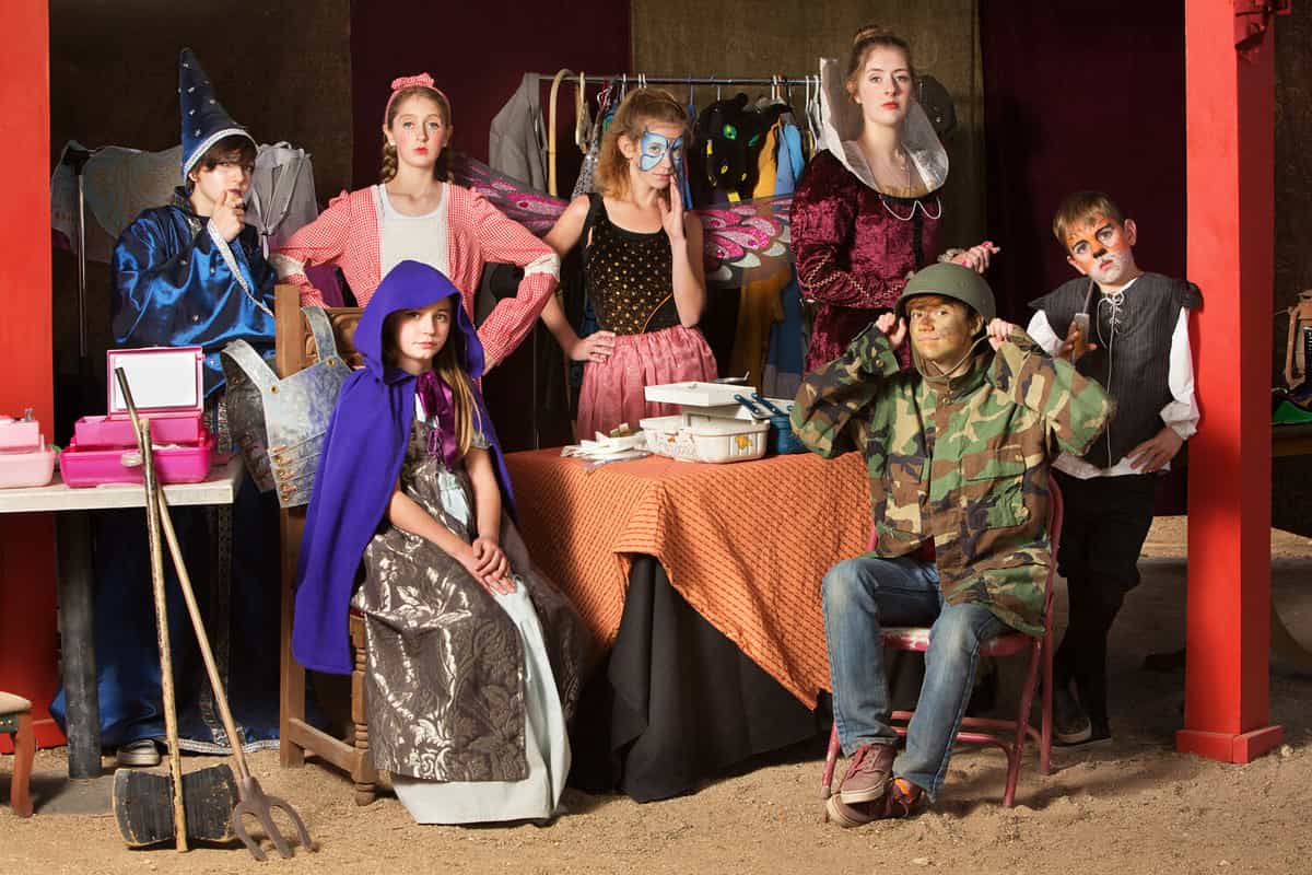 Seven young theater students prepare in the dressing room wearing their costumes