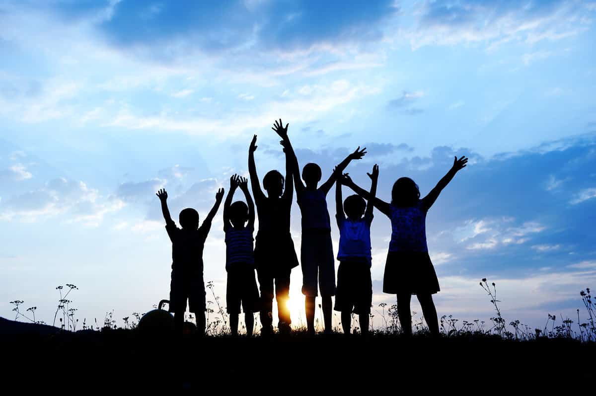 group of happy children playing on meadow, blue sky, summertime