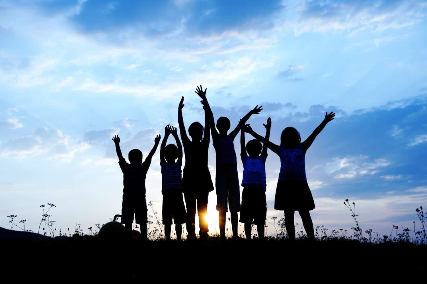 group of happy children playing on meadow, blue sky, summertime