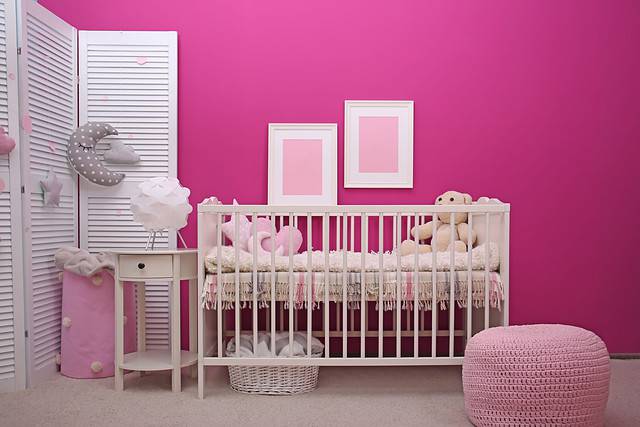 Baby room interior with crib near color wall