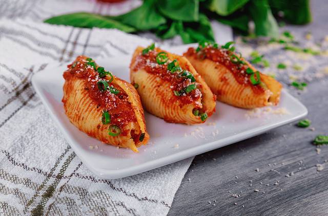 Shells pasta stuffed with a ricotta cheese, meat and basil leaves