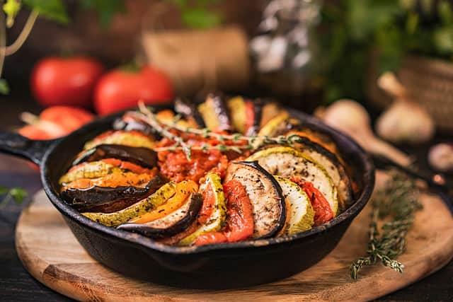 Ratatouille made of zucchini, eggplants, peppers, onions, garlic and tomatoes slices with aromatic herbs.