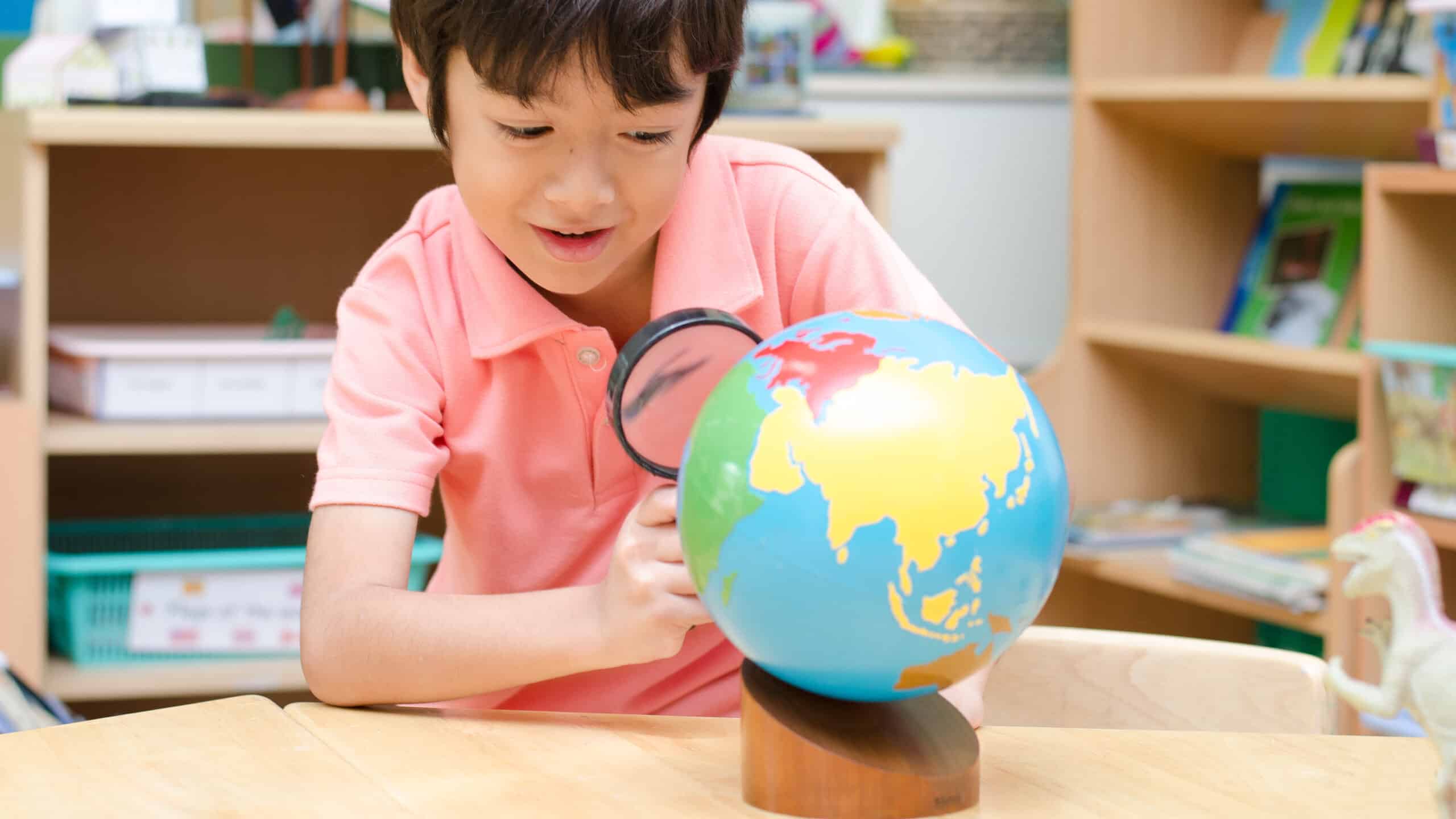 Little boy looking at Montessori globe