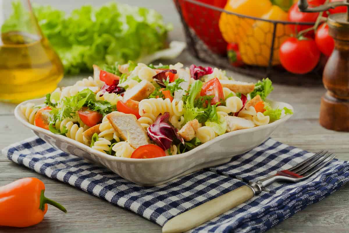 Delicious pasta salad with green lettuce, tomatoes and roasted chicken.