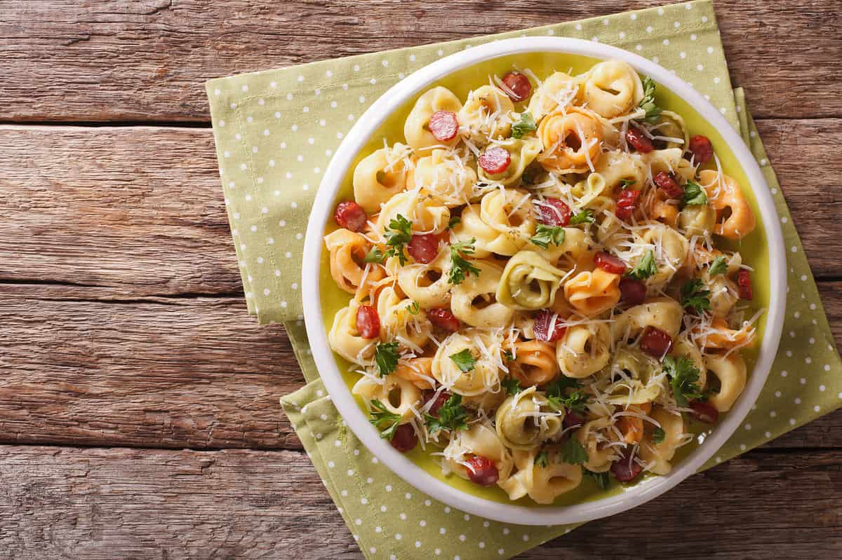 Italian colored tortellini with parmesan and sliced sausages