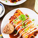 Chicken enchiladas garnished with green onions and sour cream