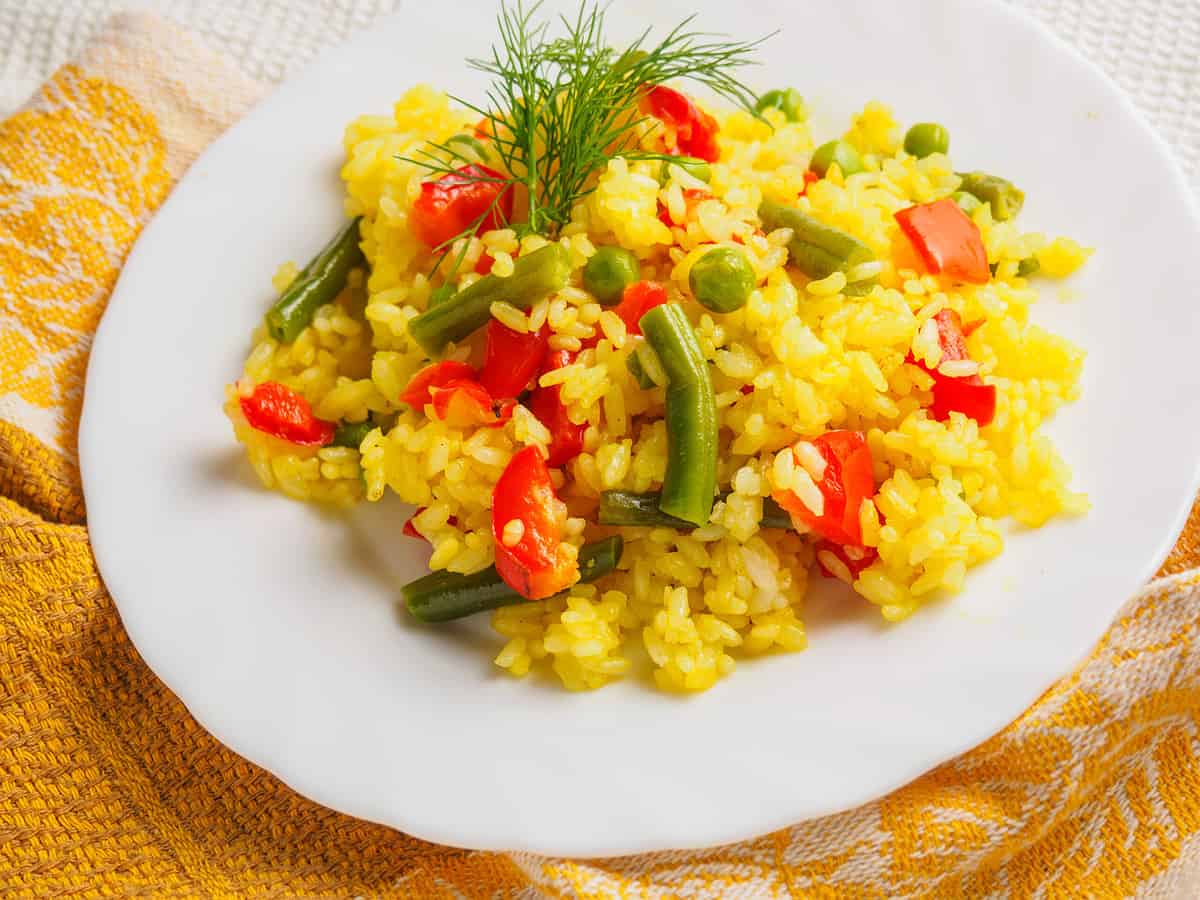 pilaf with meat with greens on a white plate.